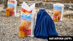زن افغان در حال دریافت کمک از سازمانهای امداد رسان - تصویر از آرشیف 