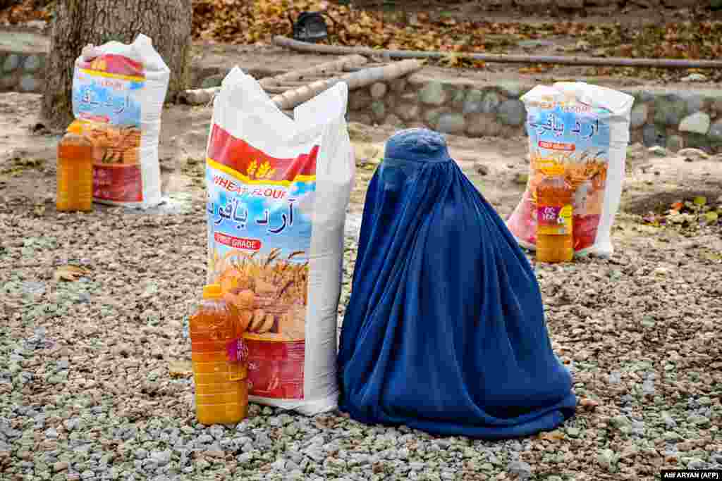  A woman sits next to food aid distributed by a local charity foundation in Mazar-i-Sharif, Afghanistan. &nbsp; 