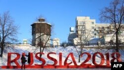 A woman poses for pictures while standing behind giant letters reading "Russia 2018" in central Yekaterinburg on January 30 as Russia marks 500 days until the start of the FIFA World Cup 2018.