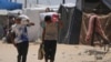 Palestinezët duke bartur ushqim dhe ndihmë humanitare të shpërndarë nga GHF-ja. 28 maj 2025. 