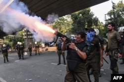 A policeman fires tear gas shells to disperse supporters of former Prime Minister Imran Khan's Pakistan Tehreek-e-Insaf (PTI) party in Lahore on October 5.