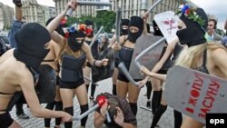 Members of the activist group FEMEN, dressed in scanty "riot police" outfits, pretend to beat up a reporter during a rally against censorship and repression in the Ukrainian media.