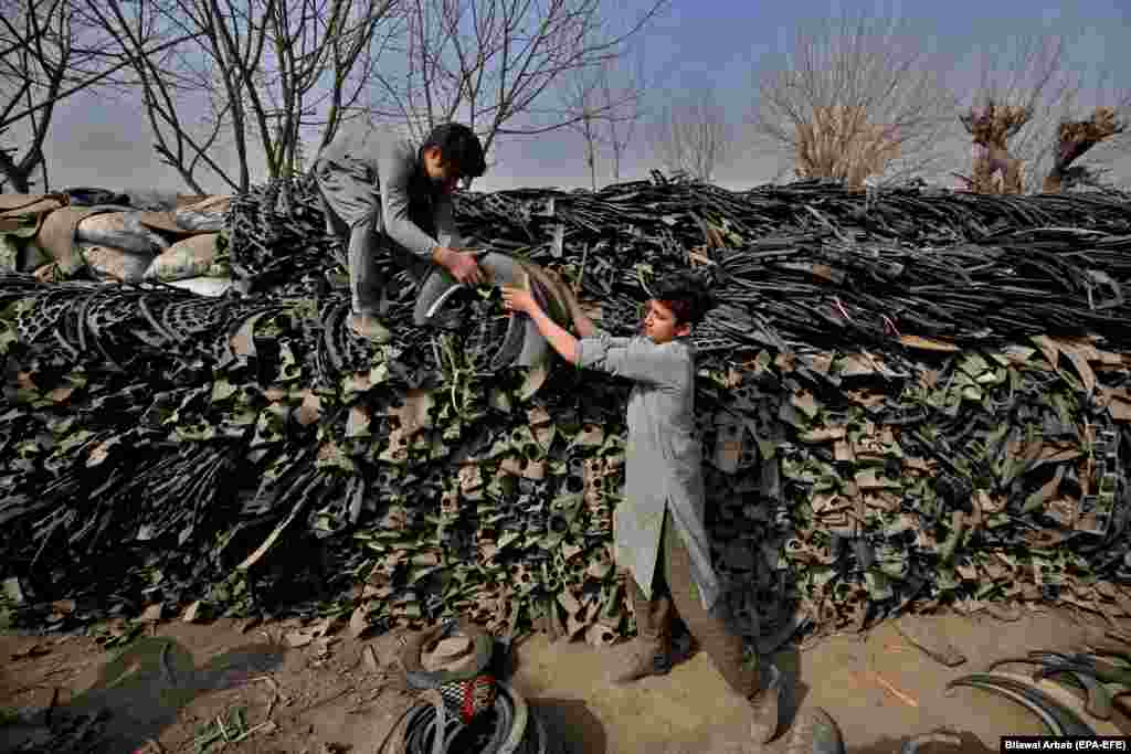 Рабочыя загружаюць кавалкі выкарыстаных шын на перапрацоўку ў Пэшавары, Пакістан. (epa-EFE/Bilawal Arbab)