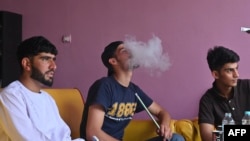 Tinerii fumează narghilea într-o cafenea din Kabul, pe 19 iunie 2021.