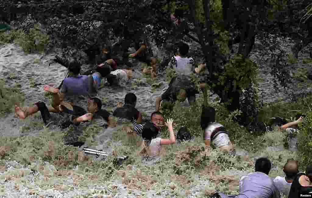 People struggle as waves from a tidal bore surge past a barrier on the banks of the Qiantang River in Haining, Zhejiang Province, China.