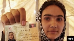 A woman shows her voter registration card in Parwan Province