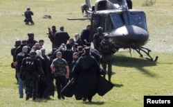 Security personnel escort Patriarch Portfirije and Bishop Joanikije to a helicopter near the monastery in Cetinje on September 5.