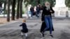 A woman wearing a protective mask plays with a child near Pincio Terrace, in Rome, Italy October 13, 2020.