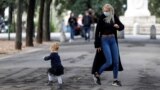 A woman wearing a protective mask plays with a child near Pincio Terrace, in Rome, Italy October 13, 2020.