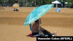 Un bărbat pe plaja urbană din Parcul La Izvor, Chișinău. Specialiștii recomandă să evităm expunerea prelungită la soare și să folosim creme cu protecție solară pentru a ne proteja.