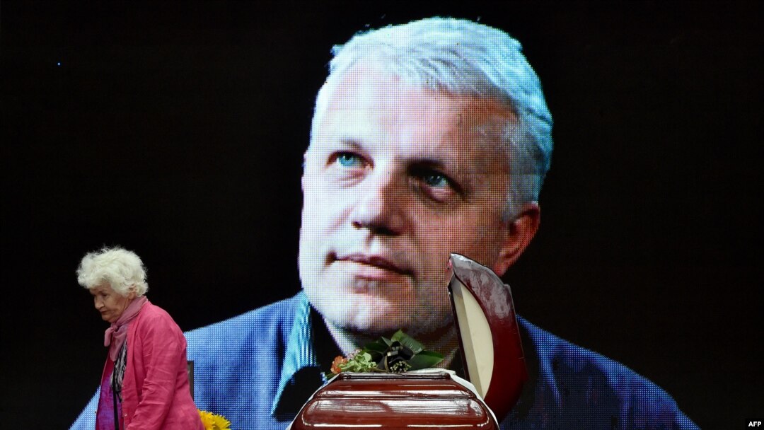 A woman pays tribute near the casket and portrait of Belarus-born journalist Pavel Sheremet, who was killed in a car bomb in central Kyiv in 2016. (file photo)