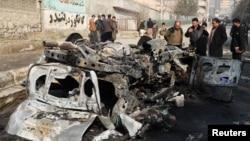Afghan officials inspect the wreckage of a burnt car at the site of a bomb blast in Kabul on January 10.