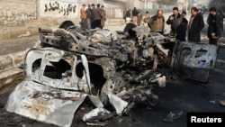 Afghan officials inspect the wreckage of a burnt car at the site of a bomb blast in Kabul on January 10.