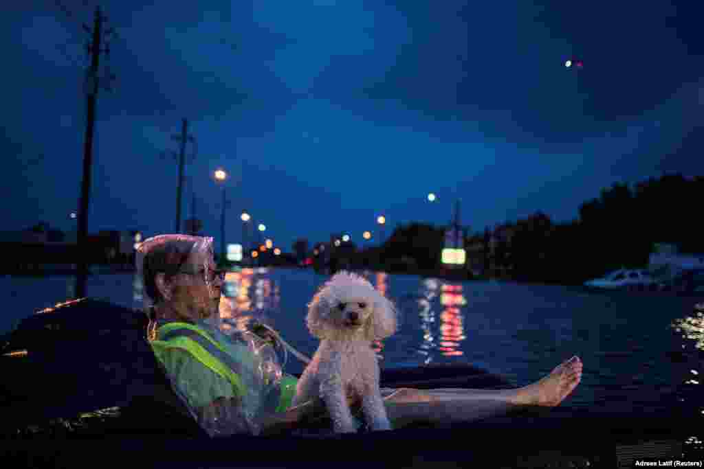 A rescue helicopter hovers in the background as an elderly woman and her poodle use an air mattress to float above flood waters from Tropical Storm Harvey while waiting to be rescued from Scarsdale Boulevard in Houston, Texas, on August 27. (Reuters/Adrees Latif)