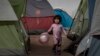 MEXICO -- A girl holds a balloon as she walks among tents inside an empty warehouse used as a shelter set up for migrants in downtown Tijuana, January 2, 2019