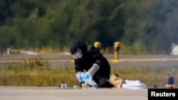 A police officer wearing protective clothing examines evidence at Germany's Leipzig Airport on August 5 after two incidents involving drones occurred. 