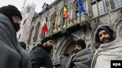 Asylum seekers from Afghanistan wrap themselves in blankets outside the Grand Place in Mons, Belgium, on December 23.