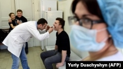 A doctor examines a teenager prior to a vaccination against measles in the Ukrainian city of Lviv. file photo)