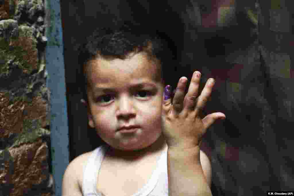 A Pakistani child shows his finger after being marked that he had received the polio vaccine in Lahore, Pakistan, on April 24. A Pakistani health official says two new polio cases have been reported in the country&#39;s northwest despite efforts against the crippling disease. Meanwhile, Pakistani health officials suspended the campaign following the killings in less than a week of a health worker and two policemen escorting vaccination teams. (AP/K.M. Chaudary)