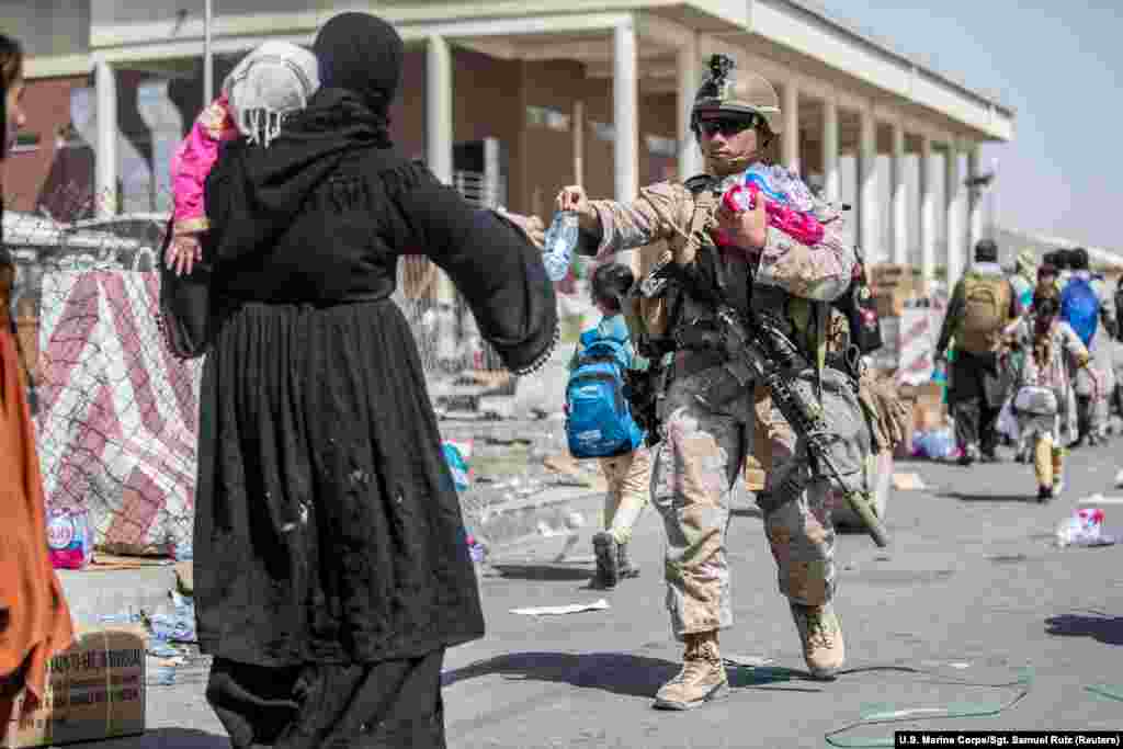 A U.S. Marine provides water to families during an evacuation at Kabul airport on August 22.&nbsp;