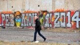 Ukraine -- A man walks past a graffito reading "Revolution 2014" on a building in central Kyiv, February 17, 2014