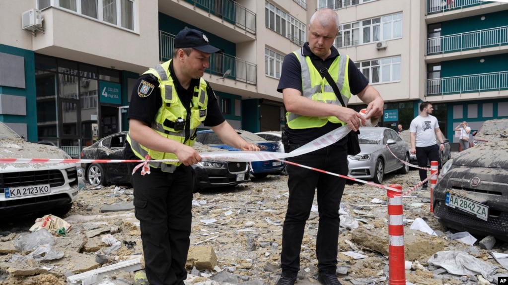 Police officers cordon off an area next to an apartment building damaged by a Russian attack in Kyiv on June 24. 
