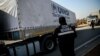 A worker stands as a Syria-bound truck, loaded with humanitarian aid, gets ready to leave a UN transhipment hub near the Turkish-Syrian border. (file photo)