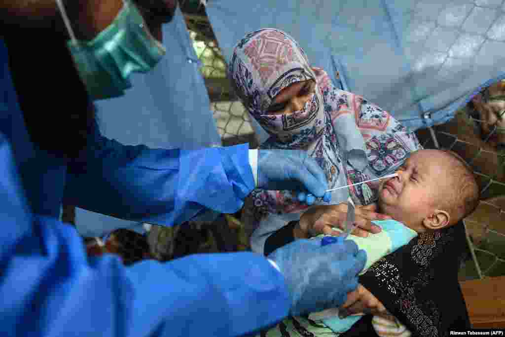 A health official takes a swab sample from a child to test for the coronavirus at a testing site in Karachi, Pakistan. (AFP/Rizwan Tabassum)