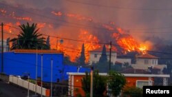 Lava teče iza kuća nakon erupcije vulkana u Španiji, 20. 9. 2021.