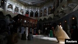 FILE: A woman clad in burqa walks in the hallway of the tomb of Sufi saint Syed Usman Marwandi, also known as Lal Shahbaz Qalandar, in Sehwan Sharif, in Pakistan's southern Sindh Province.