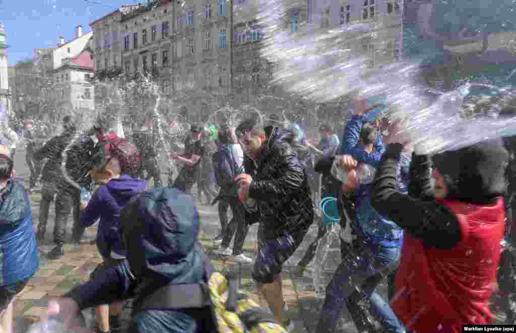 Ukrainians pour water on each other on a street in the western Ukrainian city of Lviv. The custom &nbsp;is an ancient spring rite of cleansing that takes place on the first Monday after Orthodox Easter. (epa/Markiian Lyseiko)