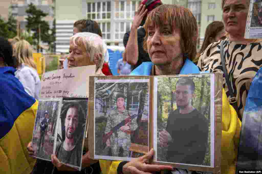 Люди тримають фотографії своїх зниклих на війні родичів у сподіванні, що хтось зі звільнених військовополонених впізнає їх