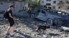 Мужчина выгуливает собаку на месте попадания в жилой дом во время ночной атаки на Киев, 20 августа 2026 года