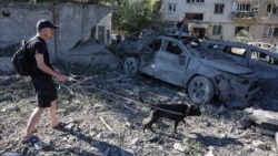 Мужчина выгуливает собаку на месте попадания в жилой дом во время ночной атаки на Киев, 20 августа 2026 года