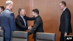 Američki specijalni izaslanik Steve Witkoff i ukrajinski predsjednik Volodimir Zelenski pozdravljaju se u Berlinu 14. decembra. Njemački kancelar Friedrich Merz (desno) posmatra.