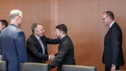 US special envoy Steve Witkoff and Ukrainian President Volodymyr Zelenskyy greet each other in Berlin on December 14. German Chancellor Friedrich Merz (r) watches.