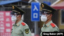 "Жаңа вирус ошағы" деп танылған "Синьфади" ірі базардың кіре берісінде тұрған полиция қызметкерлері. Пекин, 13 маусым 2020 жыл.