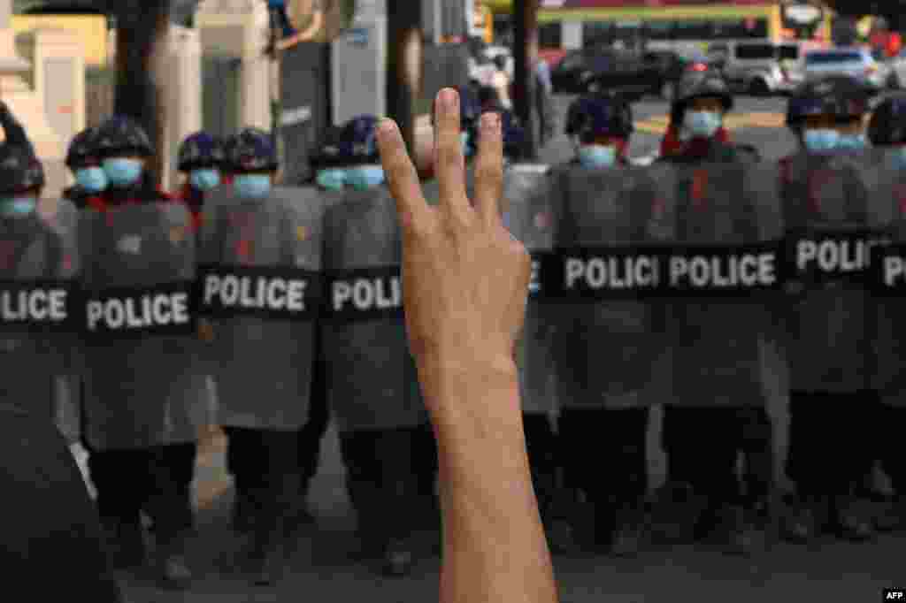 Një protestues ka ngritur tre gishta derisa policia ka bllokuar një rrugë gjatë një demonstrate kundër puçit ushtarak në Yangon, 6 shkurt, 2021. (YE AUNG THU/AFP)