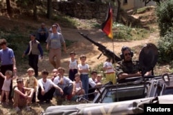 Një ushtar gjerman përcillet nga një grup refugjatësh kosovarë në Kukës të Shqipërisë, prej ku trupat do të niseshin drejt Kosovës, për ta hapur rrugën e kthimit të qindra mijëra refugjatëve.