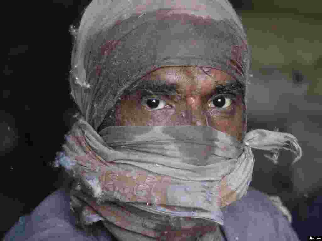 Saeed, 38, poses for a photograph while working in a cotton factory in Karachi, Pakistan. (Athar Hussain for Reuters)