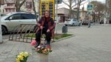 O pensionară vinde flori în centrul Tiraspolului, în apropierea unei case de schimb valutar.