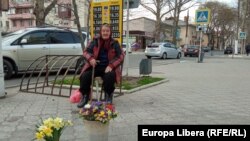 O pensionară vinde flori în centrul Tiraspolului, în apropierea unei case de schimb valutar.