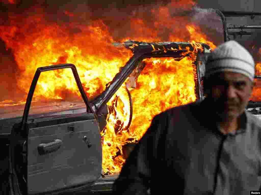 A protester walks in front of a burning police vehicle in Cairo on January 28.