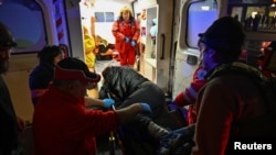 Paramedics carry an injured man into an ambulance at the site of a deadly Russian air strike in Zaporizhzhya on December 6,