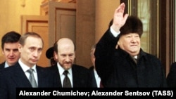 Outgoing Russian President Boris Yeltsin (right) waves as he hands over his office to Vladimir Putin (left) at Kremlin in Moscow on December 31, 1999.