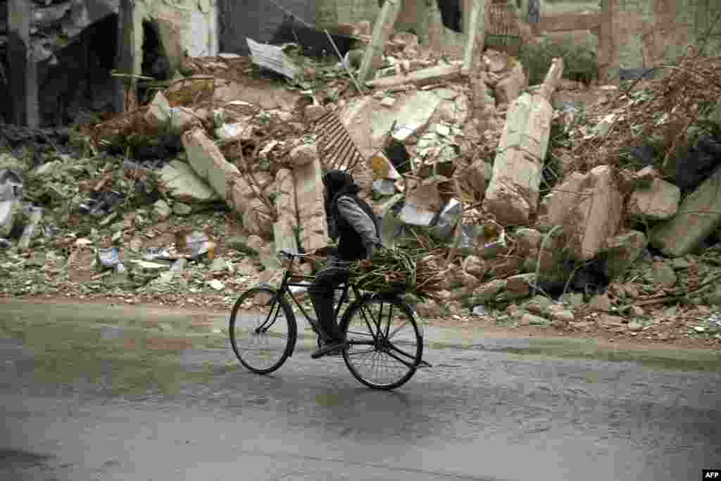 A Syrian man rides a bike past damaged buildings in the rebel-held area of Douma, east of the capital, Damascus. (AFP/Sameer al-Doumy)