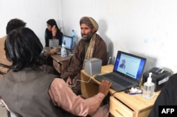 Afghan refugees provide biometric verification to an official from Pakistan's National Database and Registration Authority (NADRA) at a holding center before being deported to Afghanistan. (file photo)