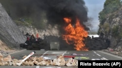 Protesters can be seen behind a barricade during a protest against the enthronement of Bishop Joanikije II in Cetinje on September 5.