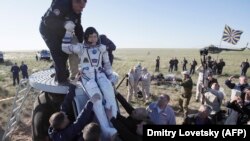 Сотрудники Роскосмоса помогают Норишиге Канаи выбраться из капсулы после приземления. Карагандинская область, 3 июня 2018 года.