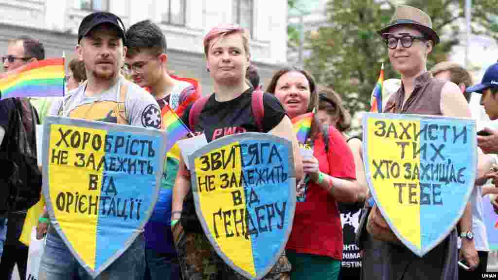 Marchers with pro-LGBT signs on the colors of the Ukrainian flag. (From left to right: &quot;Bravery doesn&#39;t depend on your orientation.&quot;/&quot;Victory doesn&#39;t depend on gender.&quot;/&quot;Protect those who protect you.&quot;)